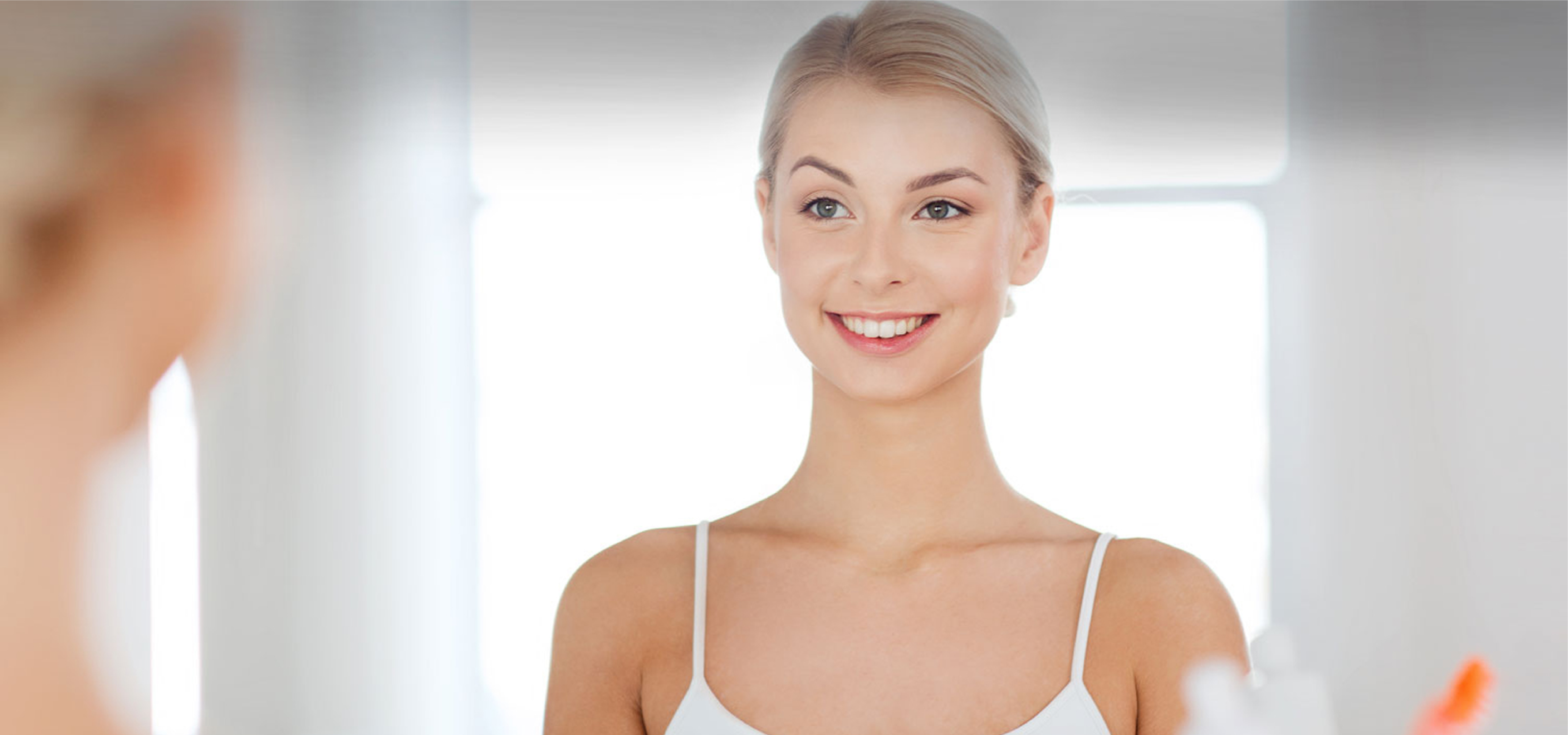 Blonde woman smiling at herself in the mirror